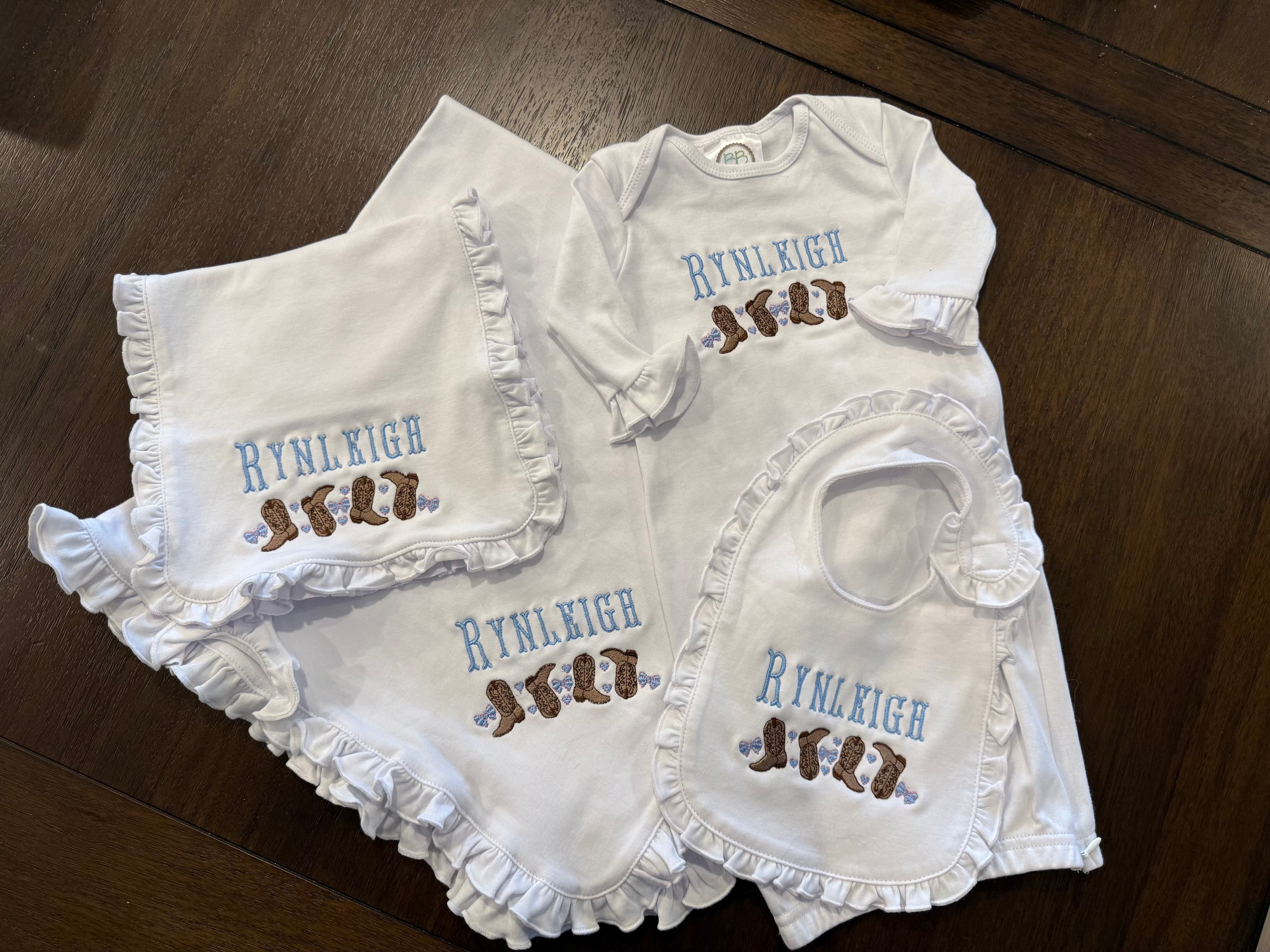 A personalized baby outfit with a matching blanket, hat, and bib